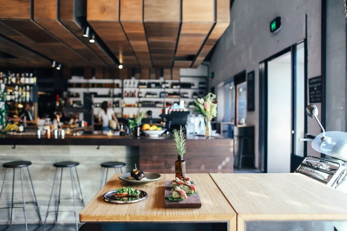 Interior de bistro cu bucătărie deschisă, mese amenajate și bar pregătit pentru clienți