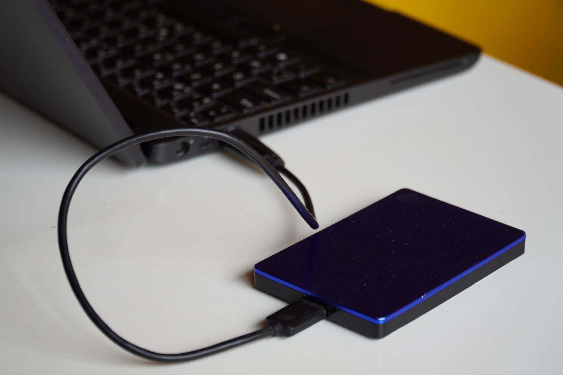 Hard disk extern conectat la un laptop pe un birou, folosit pentru copii de siguranță ale datelor