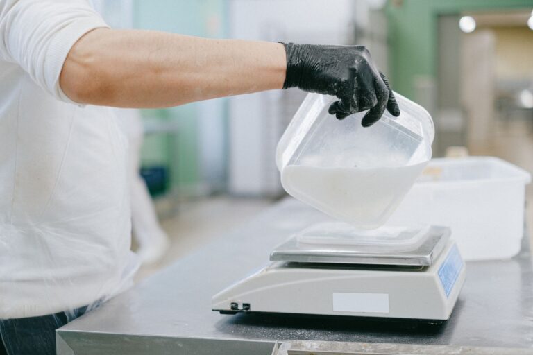 Bucătar care cântărește ingredientele unei porții pe un cântar digital, într-o bucătărie profesională